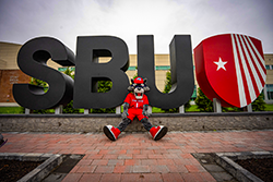 SBU mascot sits in front of large letters.